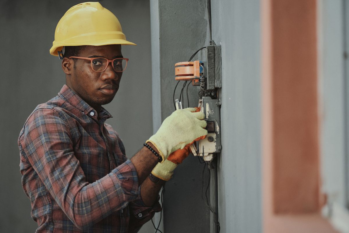 an HVAC technician beside a residential air-conditioning unit