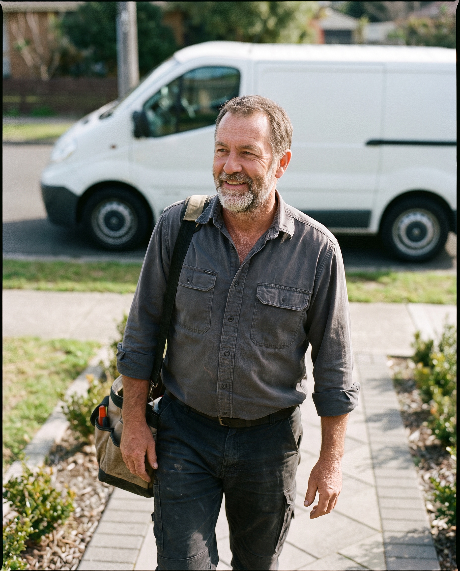 a plumber beside a service van in a suburban driveway